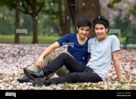 Relaxing outdoors together. Cute young gay Asian couple smiling ...