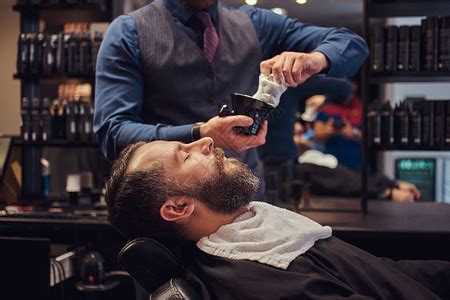 在理发店修剪胡子的男子图片-理发师在理发店用修剪器为男子刮胡子素材-高清图片-摄影照片-寻图免费打包下载