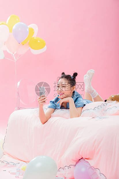 年轻女孩趴着在床上使用手机高清图片下载-正版图片507619390-摄图网
