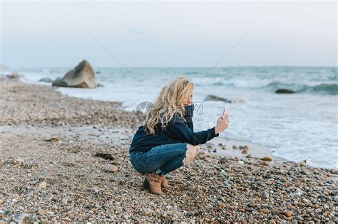 年轻女子在海滩上用手机拍照高清图片下载-正版图片501890531-摄图网