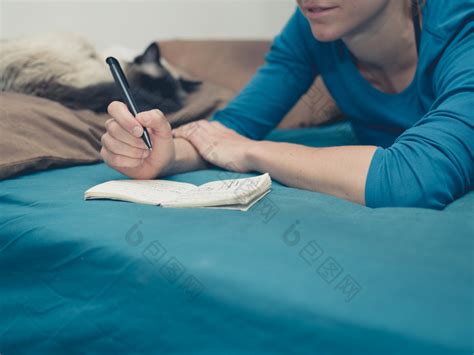 女孩趴在床上写笔记图片-包图网