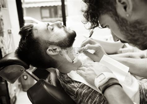 理发师使用锋利的剃刀为有胡子的人刮胡子高清图片下载-正版图片502656699-摄图网