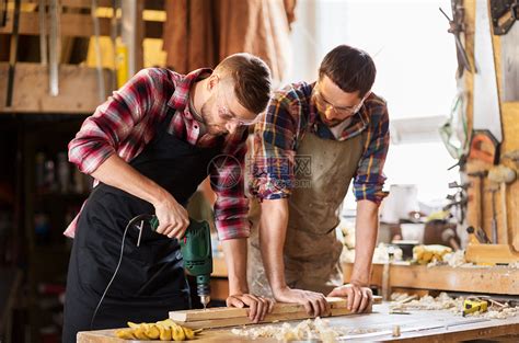 专业,木工,木工人的两个木匠与电钻钻孔木板车间车间带钻钻钻板的木匠高清图片下载-正版图片300164430-摄图网
