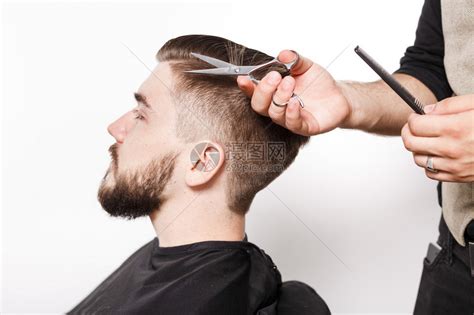 英俊的年轻理发师给留着胡子的男顾客剪新发型高清图片下载-正版图片504887746-摄图网
