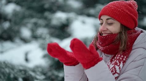 4k慢动作极端近距离脸美丽微笑的女人在针织红色无檐帽和围巾在公园在冬季户外散步。雪花飘着，女人开心地笑了视频素材_ID ...