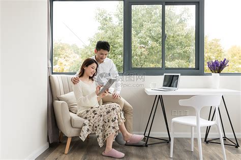 年轻夫妻幸福地坐在沙发上看平板电脑高清图片下载-正版图片500816243-摄图网