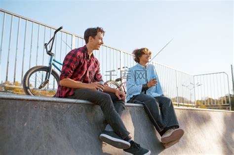 两名小轮车骑手在训练后在滑板公园休闲。合照情侣高清摄影大图-千库网