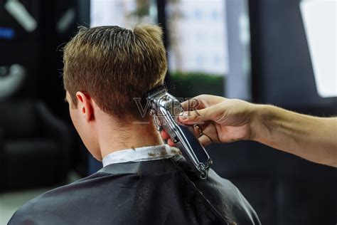 男性用电动剃须刀理发。理发师在理发店用理发器为顾客理发。男人用电动剃须刀理发照片摄影图片_ID:340877062-Veer图库
