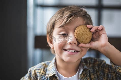 微笑的小男孩手里拿着饼干捂住眼睛看着相高清图片下载-正版图片502693508-摄图网