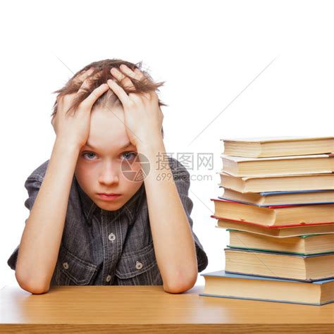 坐在书本顶着头的书桌旁的学校男孩心高清图片下载-正版图片504760641-摄图网