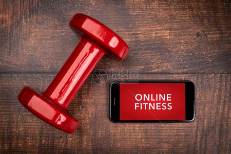 用于培训室内在线健身方案的红哑铃和智能手机木林背景App用于培训室内在线健身方案家庭在线锻炼TopViewCovid19Coro图片素材-正版 ...