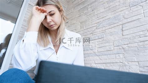 女人用痛苦而忧心忡忡的表情看着她的笔记本电脑高清摄影大图-千库网