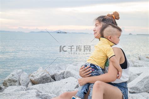 亚洲男孩和他的母亲在海边放松高清摄影大图-千库网