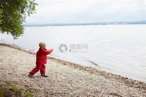 河边一个四岁的男孩把石头扔进水里。高清摄影大图-千库网