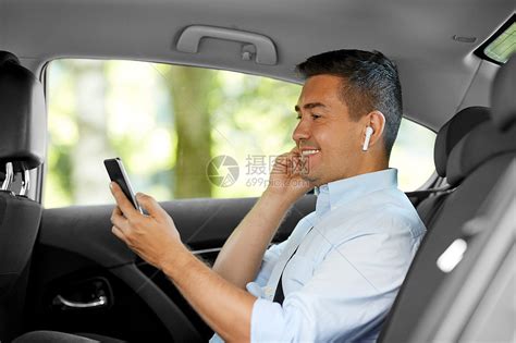 运输,商业技术微笑的男乘客商人与无线耳机用智能手机出租车后座出租车上耳机手机的乘客高清图片下载-正版图片300068825-摄图网