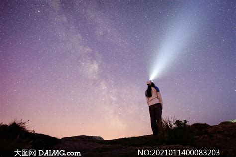 一个人站在石头上独自仰望夜空中灿烂的星河