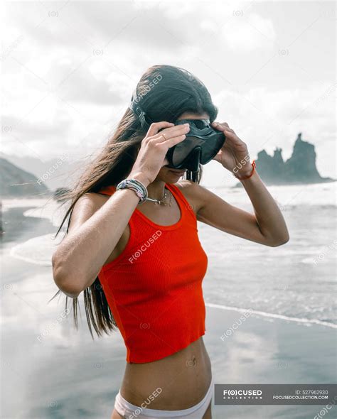 Cheerful female teenager in bikini and crop top with diving mask ...