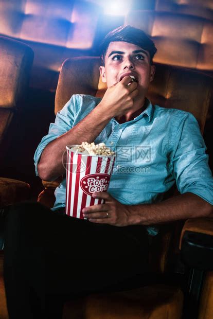 一个年轻男人在电影院看电影时微笑着享受爆高清图片下载-正版图片504006644-摄图网
