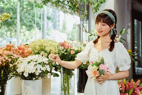 一位有吸引力和微笑的女顾客从鲜花市场摊位店和年轻的店员那里购买一束白色鲜花的肖像高清图片下载-正版图片502707936-摄图网