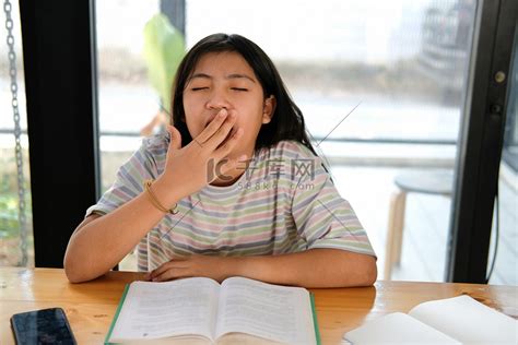 女学生在看书时打哈欠感到疲倦无聊困倦。高清摄影大图-千库网