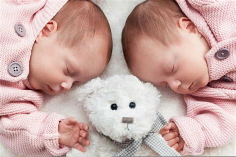 趴在白色毛毯上的双胞胎姐妹图片-戴着羊毛绒球帽的双胞胎姐妹的婴儿躺在一起素材-高清图片-摄影照片-寻图免费打包下载