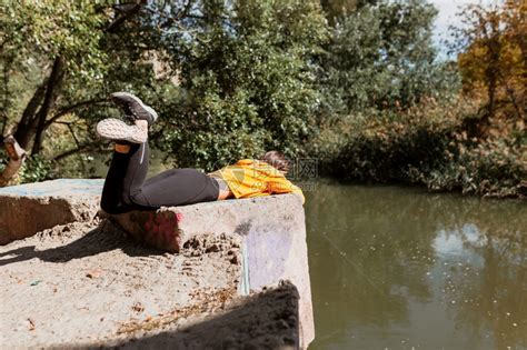 躺在河岸边休息的女人秋天躺在河岸边的女人桥观察轻松高清图片下载-正版图片307665309-摄图网
