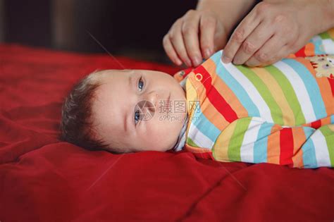 父母照顾者为躺在床上的新生男婴换尿布衣服爸妈在家照顾孩子真实的生活方高清图片下载-正版图片506023484-摄图网