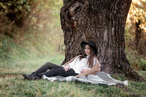 坐在大树下戴黑帽的美女高清摄影大图-千库网