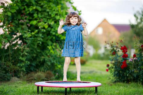 可爱的小女孩在户外蹦床上蹦蹦跳跳。照片摄影图片_ID:324363567-Veer图库