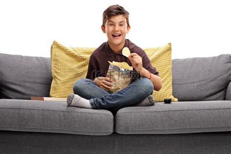 小男孩坐在沙发上吃薯片高清摄影大图-千库网
