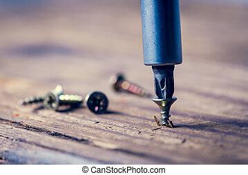 Screwing a screw into wood with a screwdriver. | CanStock