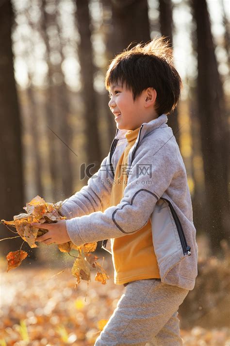 秋天户外男孩玩树叶高清摄影大图-千库网
