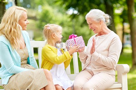 家庭,假期人的快乐的微笑孙女送礼物给她的祖母坐公园长凳上快乐的家庭公园给祖母送礼物高清图片下载-正版图片300119392-摄图网